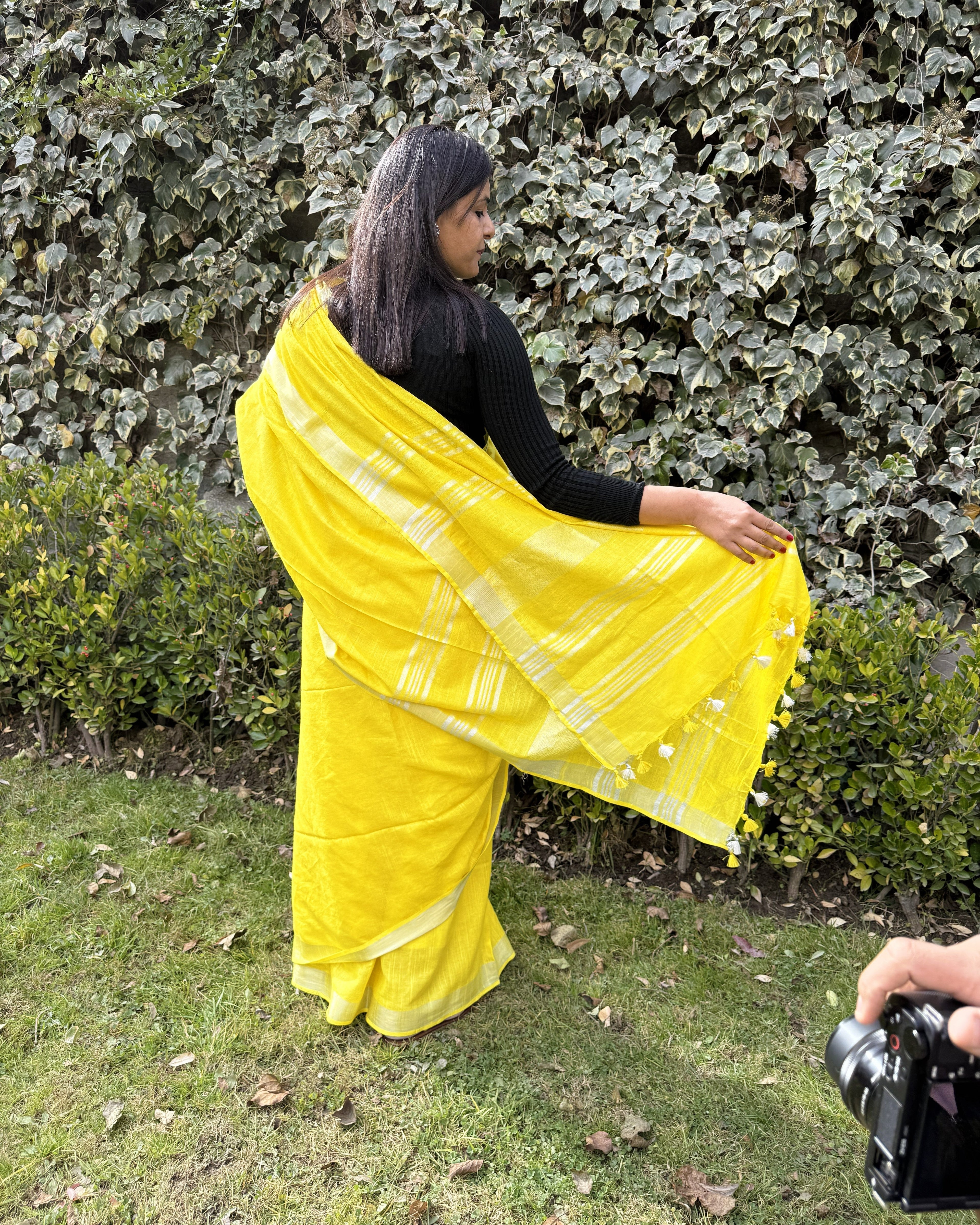 Back view of bright yellow pure linen saree with zari border showcasing pallu design and graceful fall