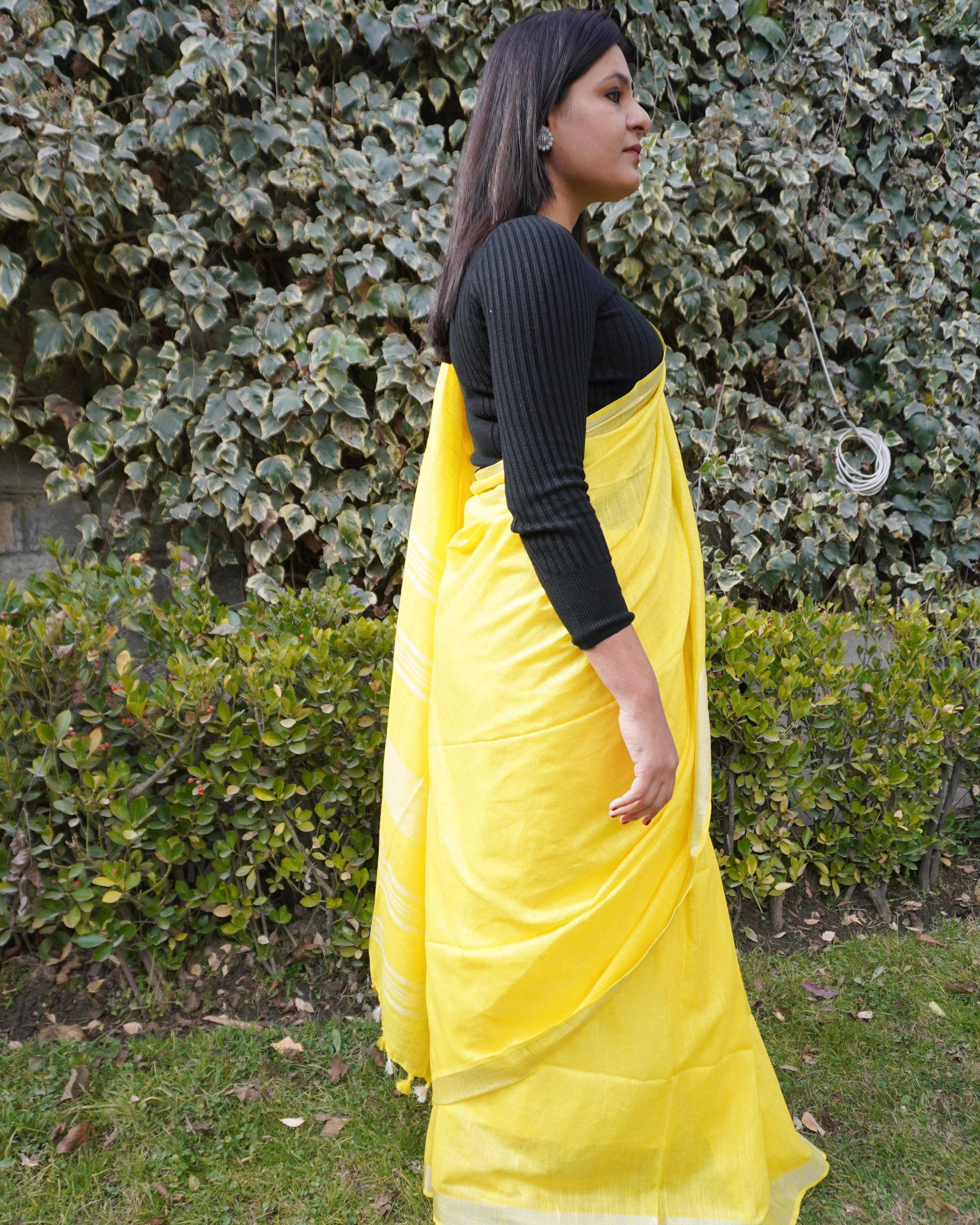 Side look of bright yellow pure linen saree with zari border displaying soft drape and border detailing