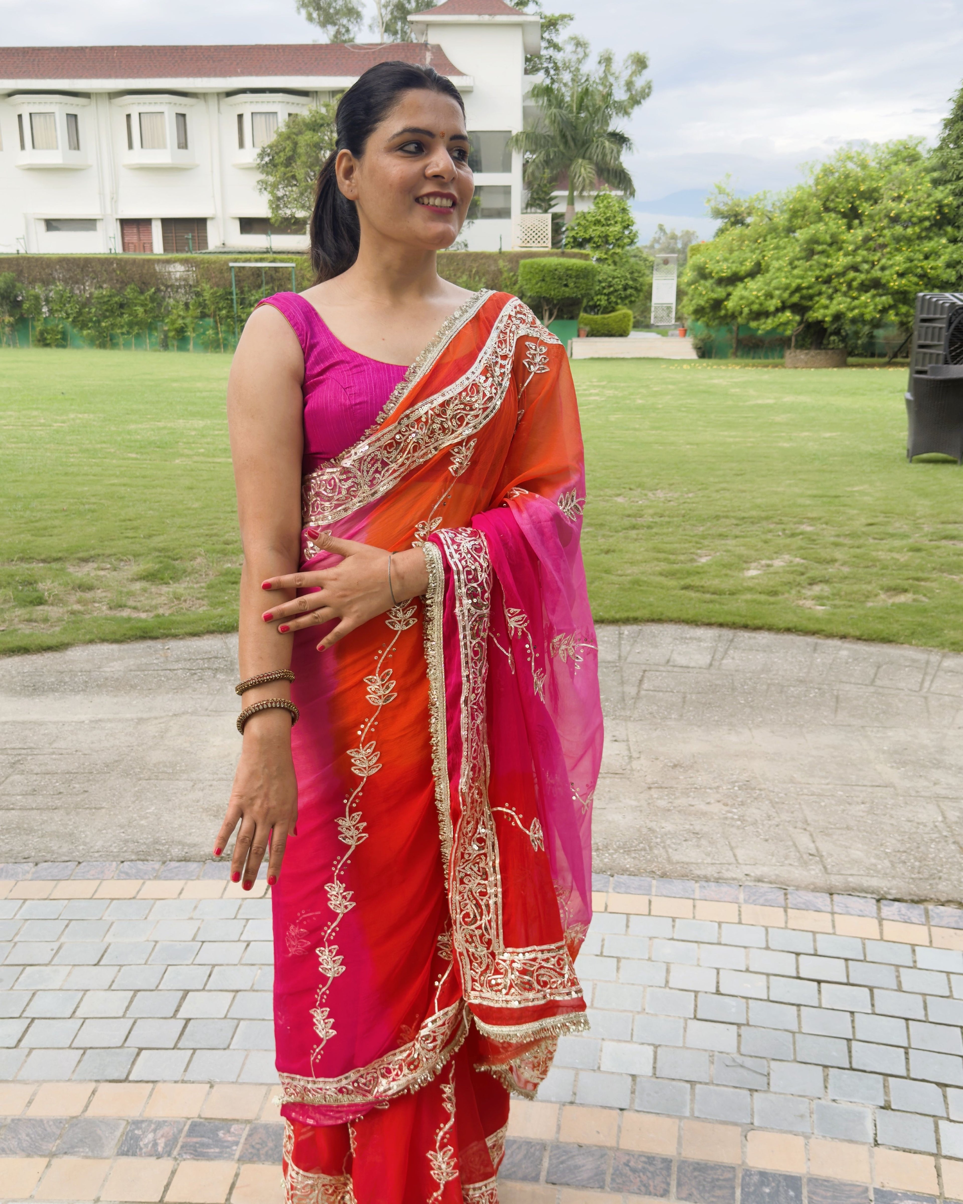 side pose wearing hot pink chiffon saree with silver gotta patti border