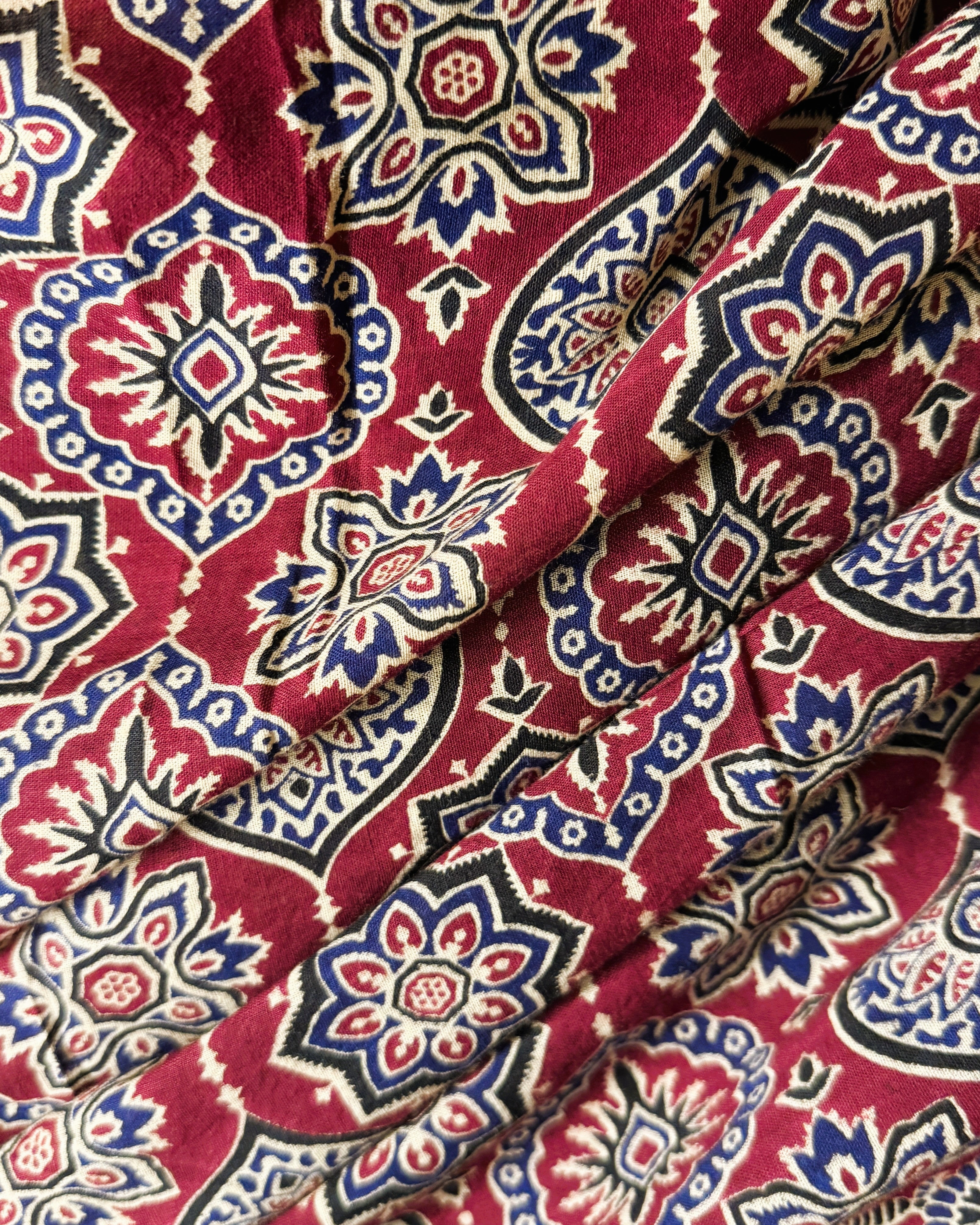 Close-up of maroon and blue Ajrakh print mul cotton saree showing intricate traditional patterns and breathable fabric texture