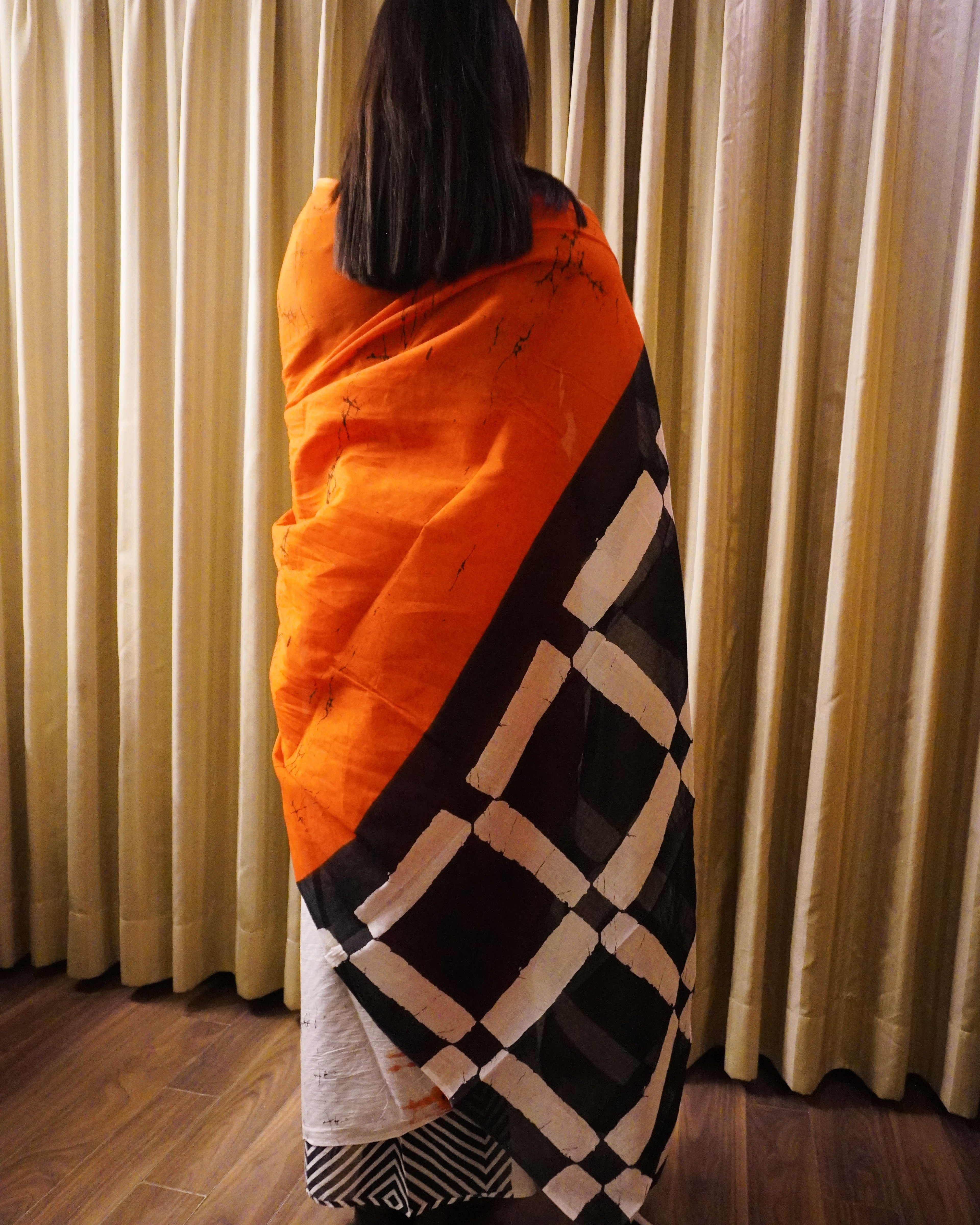 Back look of orange, black and white plain cotton saree showcasing pallu and graceful fall