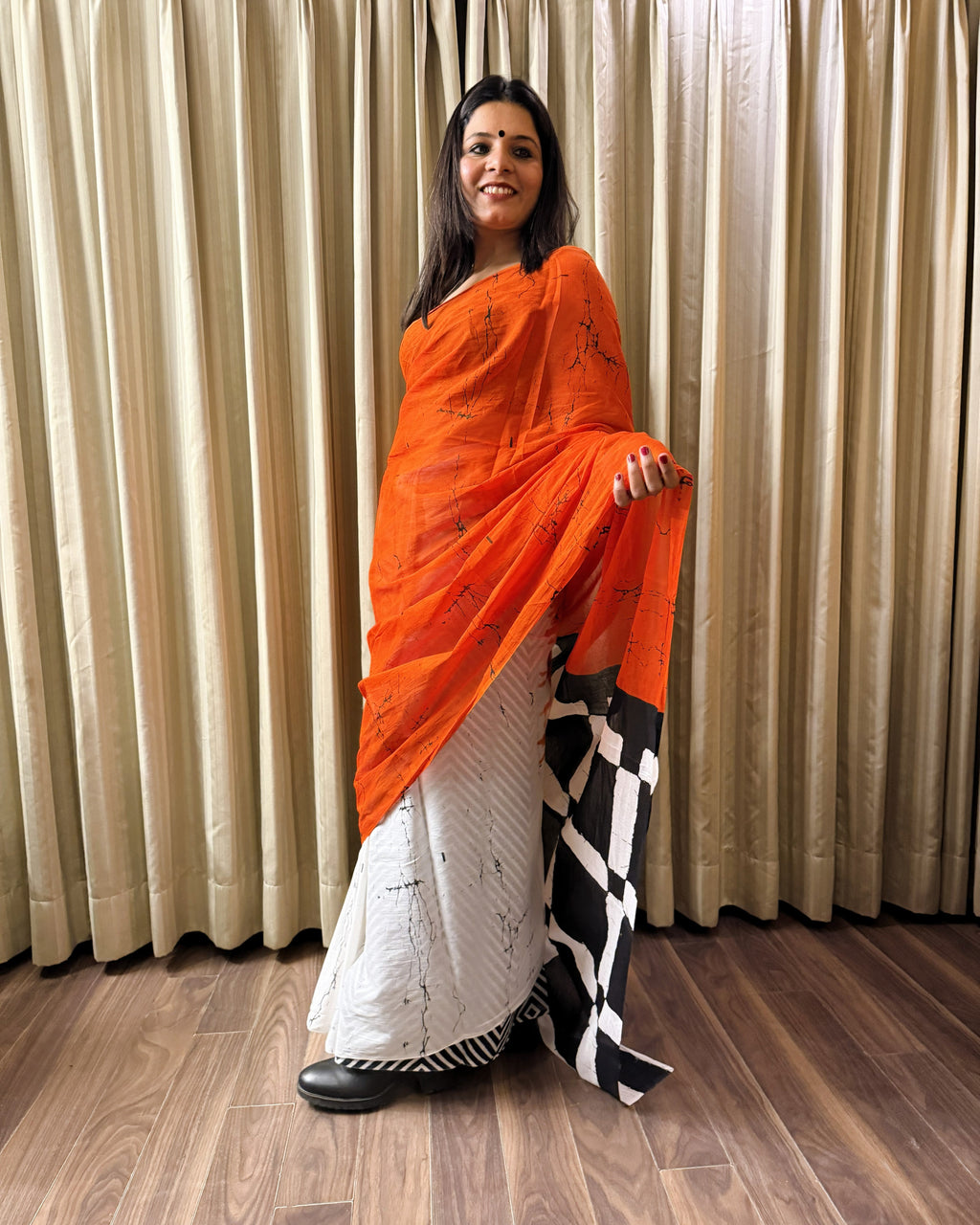 Front look of orange, black and white plain cotton saree highlighting overall flow and simplicity