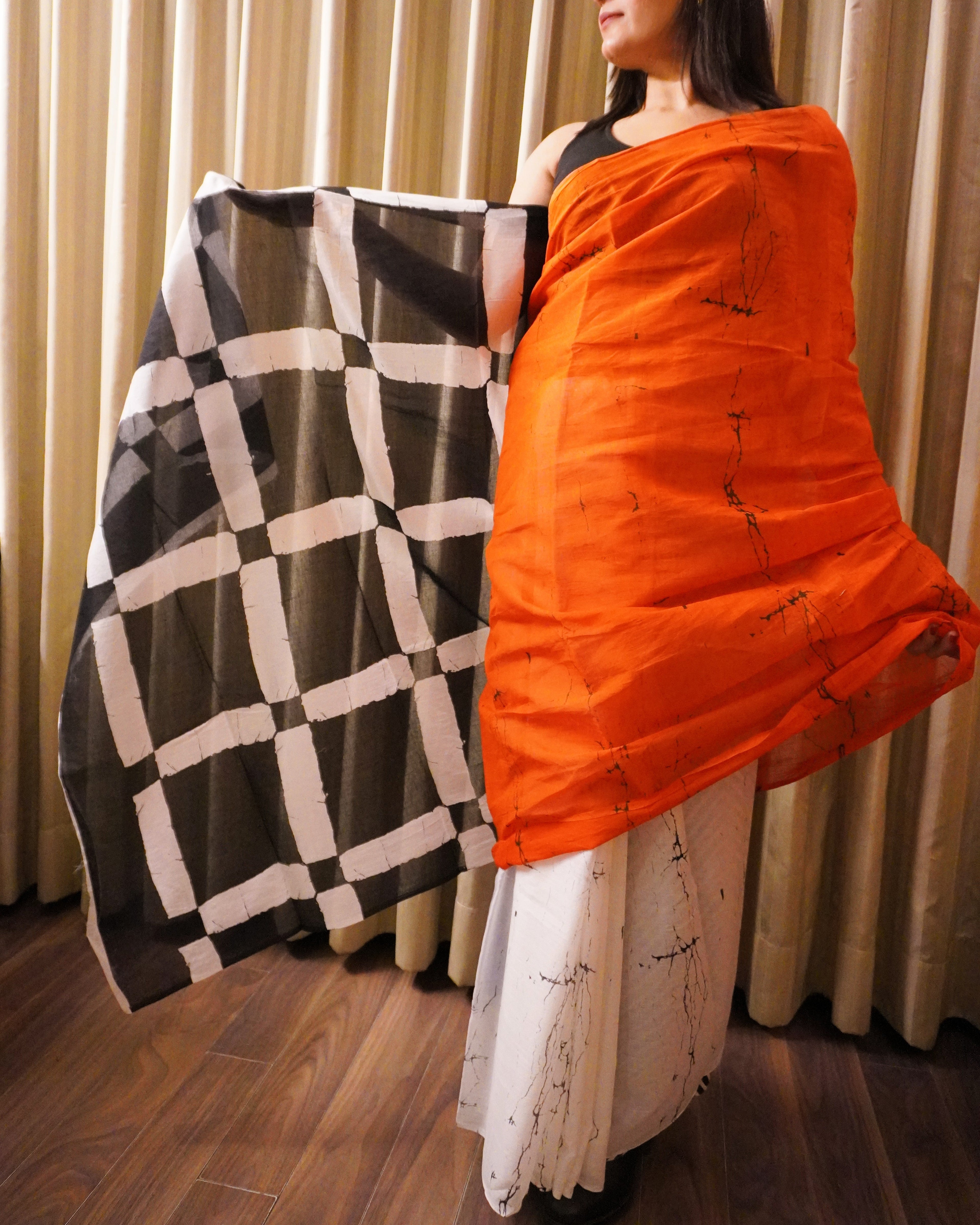 Side view of orange, black and white plain cotton saree displaying soft drape and border detailing