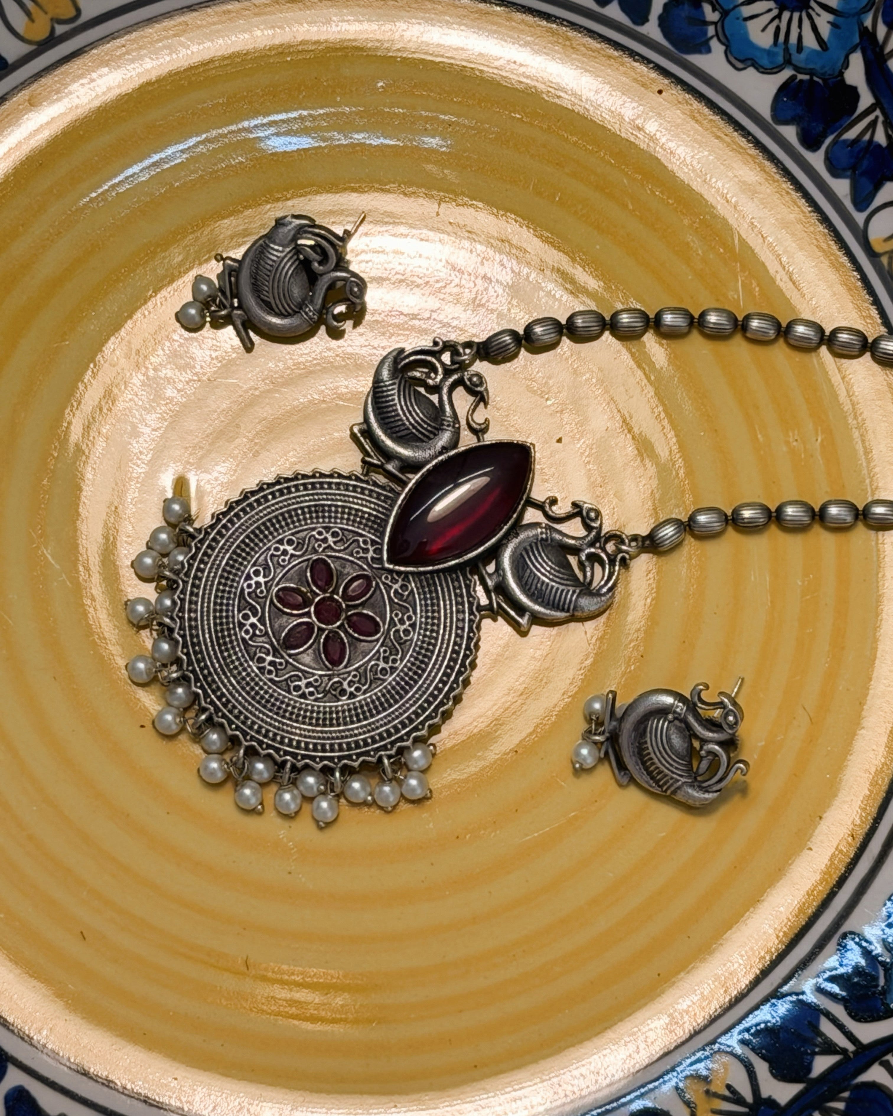 Elongated deep red stone centerpiece in statement necklace with peacock design