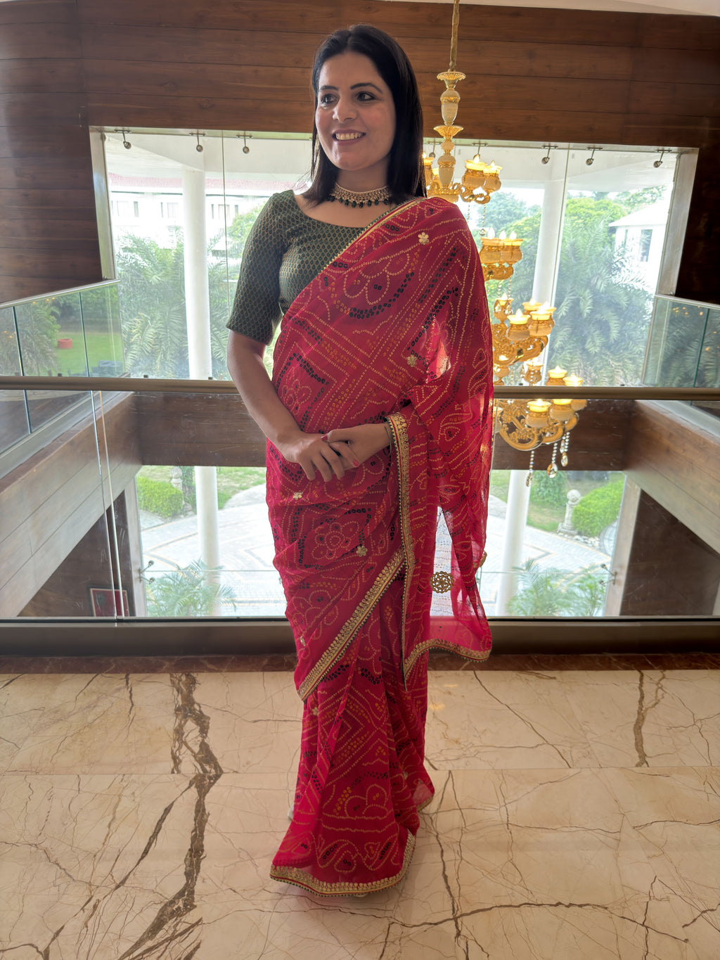 side pose wearing rani pink pure georgette bandhej saree with gotta patti border
