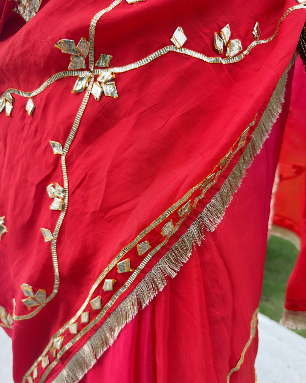 close up of red saree with intricate gold gotta patti floral and leaf work