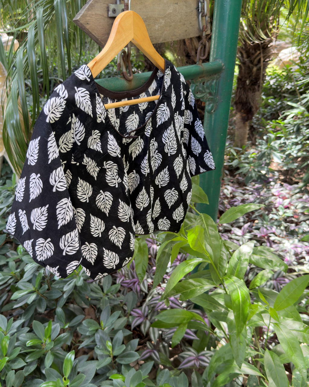 Detailed view of white botanical leaf motifs on black cotton blouse