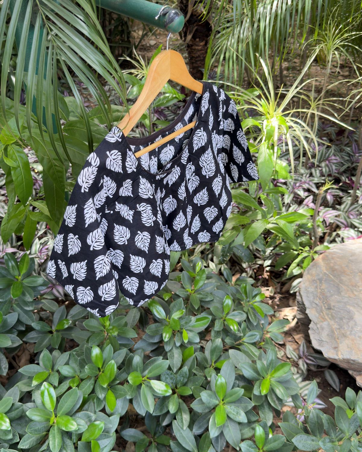 Close-up of round neckline and white leaf print on black cotton blouse