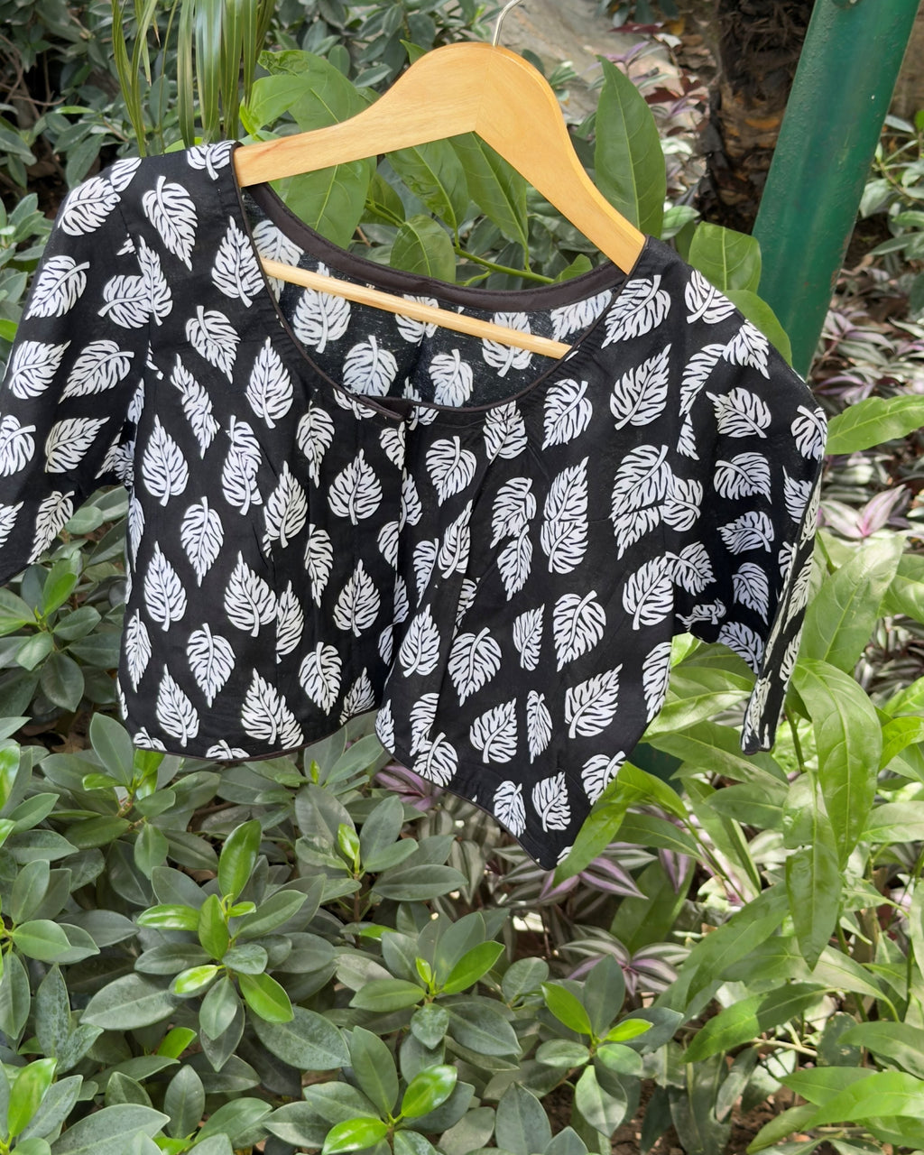 Short sleeve detail of black cotton blouse with white leaf motifs