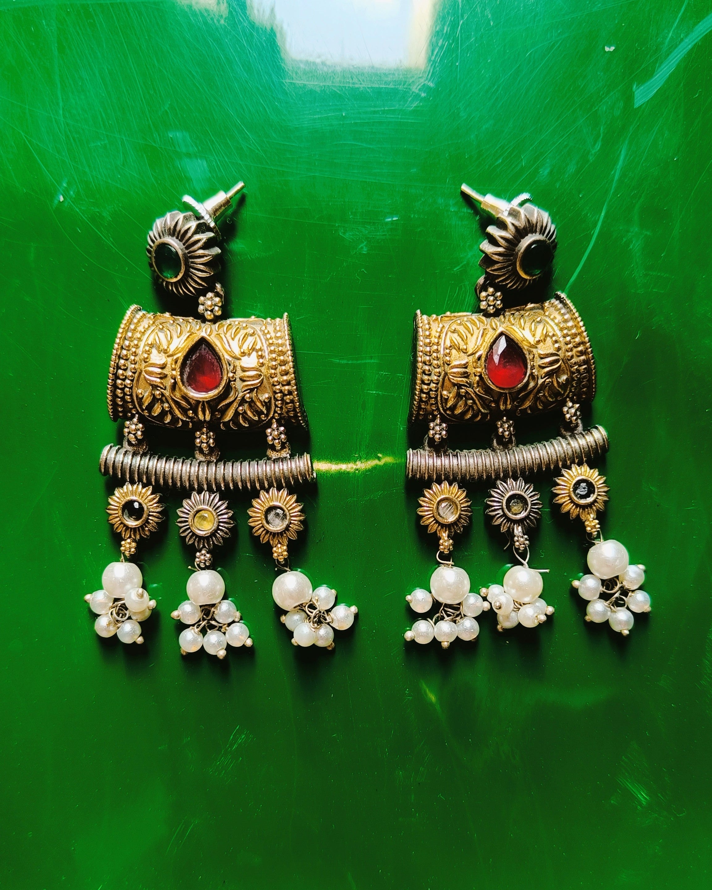 Dual tone gold and oxidised silver chandelier earrings with ruby-red stone, sunflower charms and cascading drops from the Mughal Baagh set