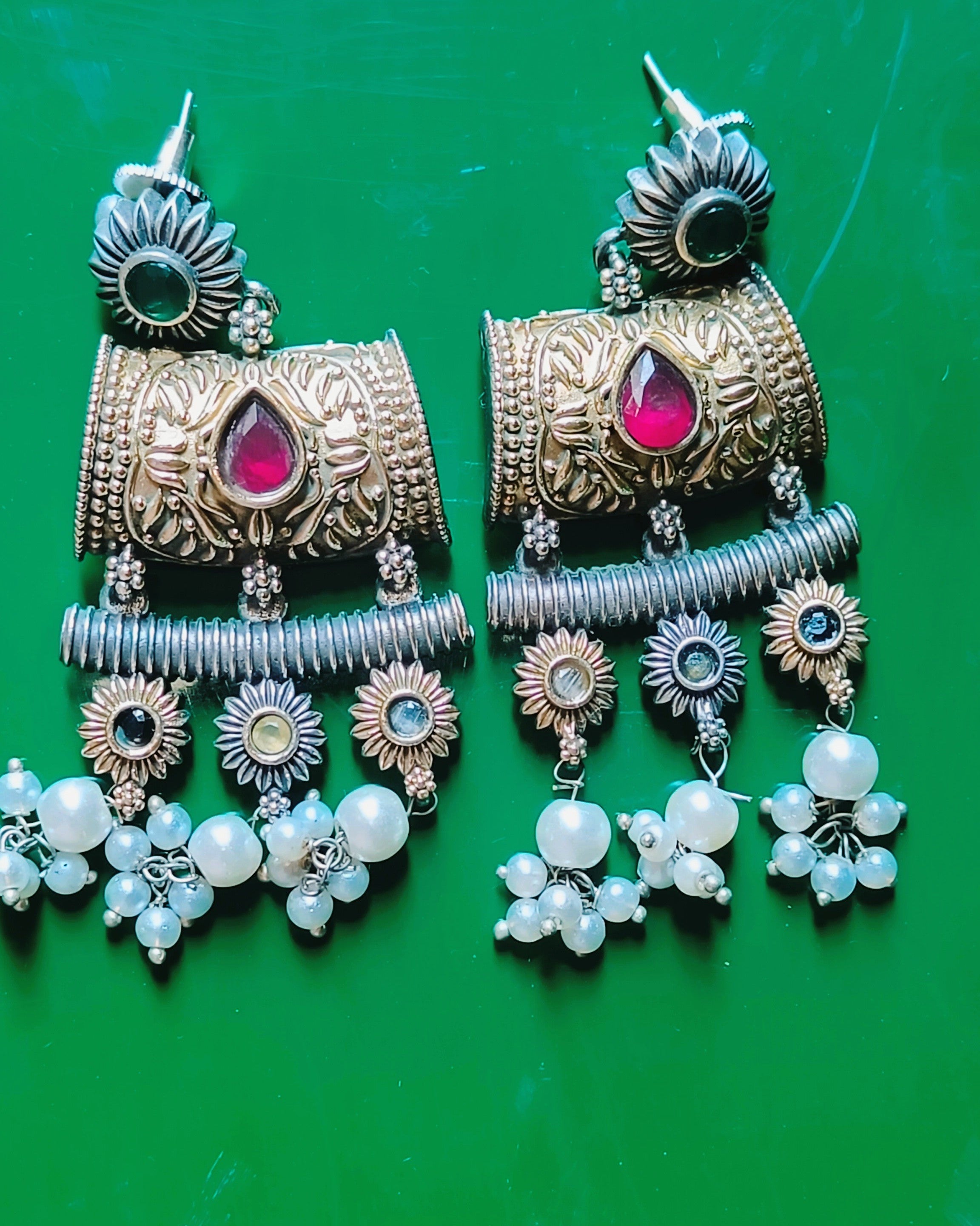 Dual tone gold and oxidised silver chandelier earrings with ruby-red stone, sunflower charms and cascading pearl drops from the Mughal Baagh set