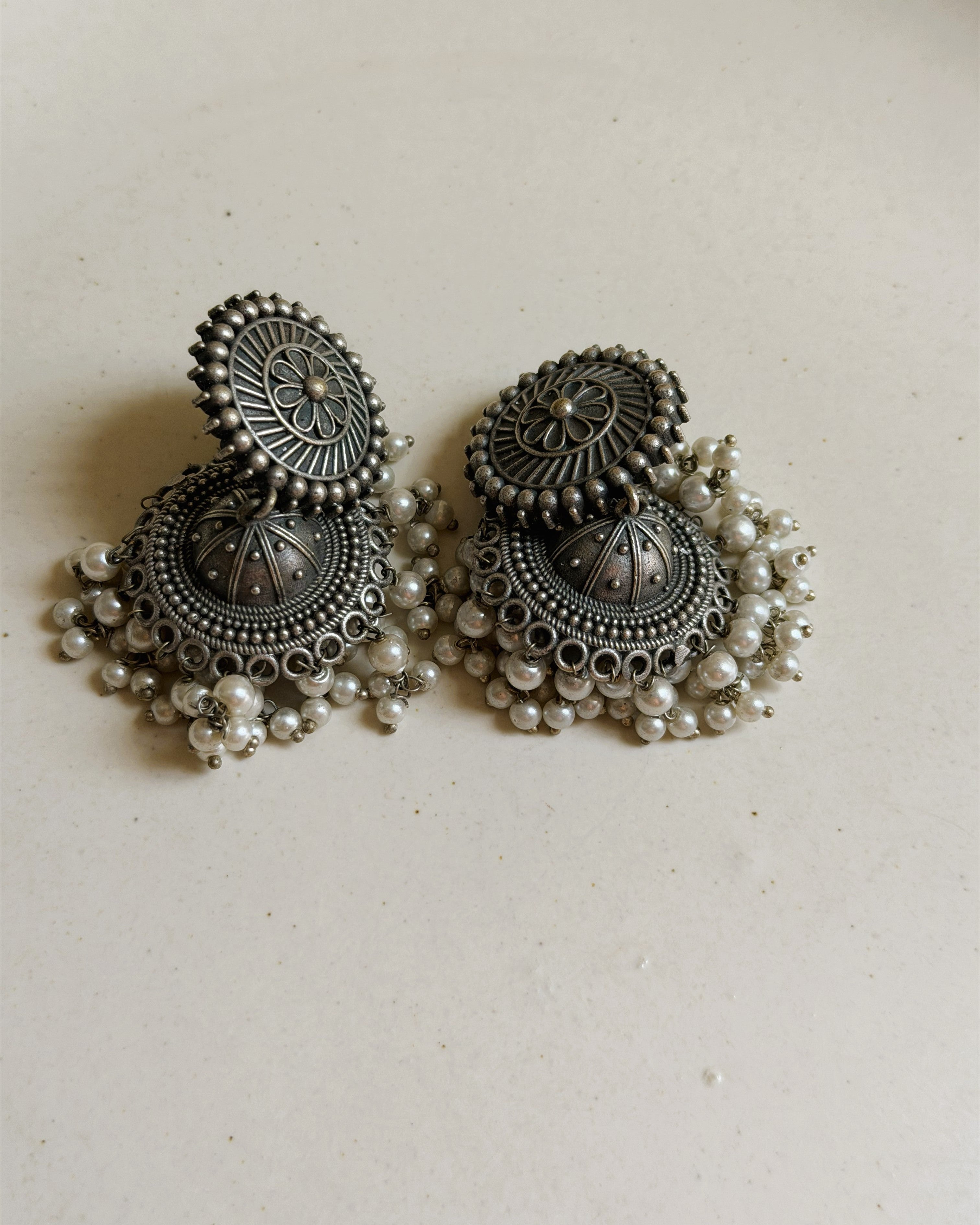 Detailed view of the domed jhumka bell with bead-dot pattern and scalloped loop base of the Pushpa antique oxidised silver earring