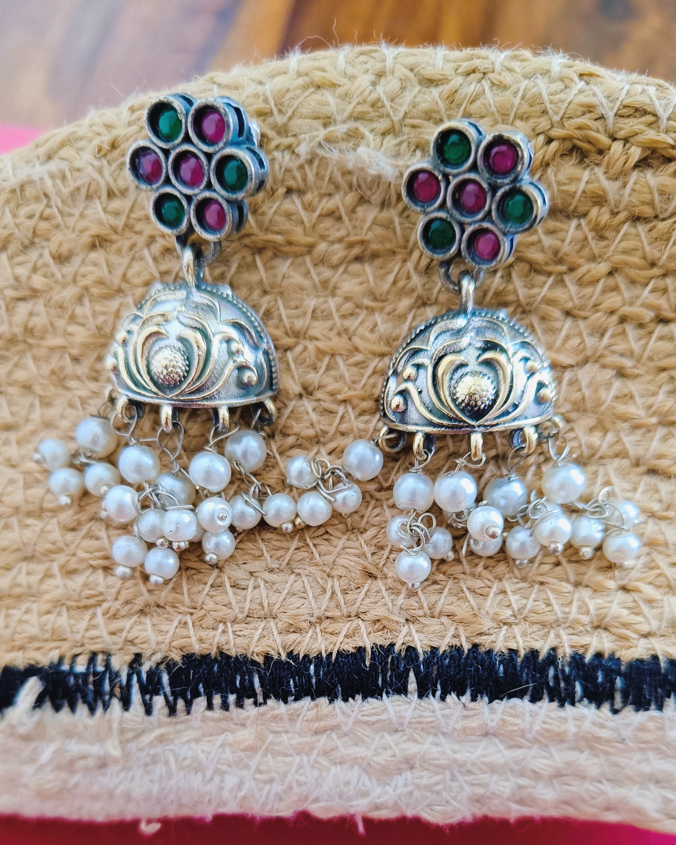 Dual tone jhumka earrings with multicolour stone flower stud, engraved gold dome, and cascading white pearl drops