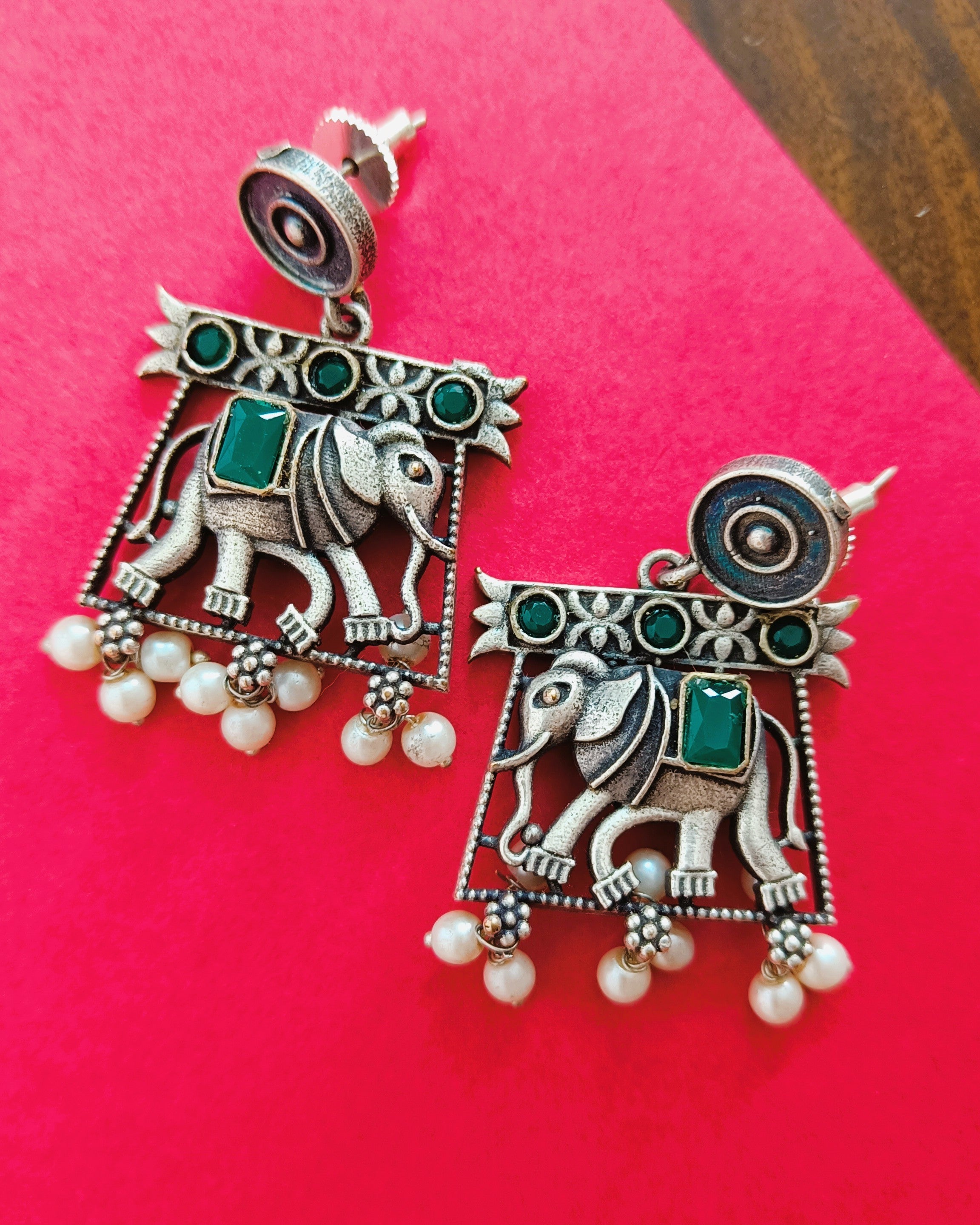 Traditional brass silver elephant-in-arch stud earrings with emerald-green stone accents and seed pearl drops from the Gajraj Emerald set