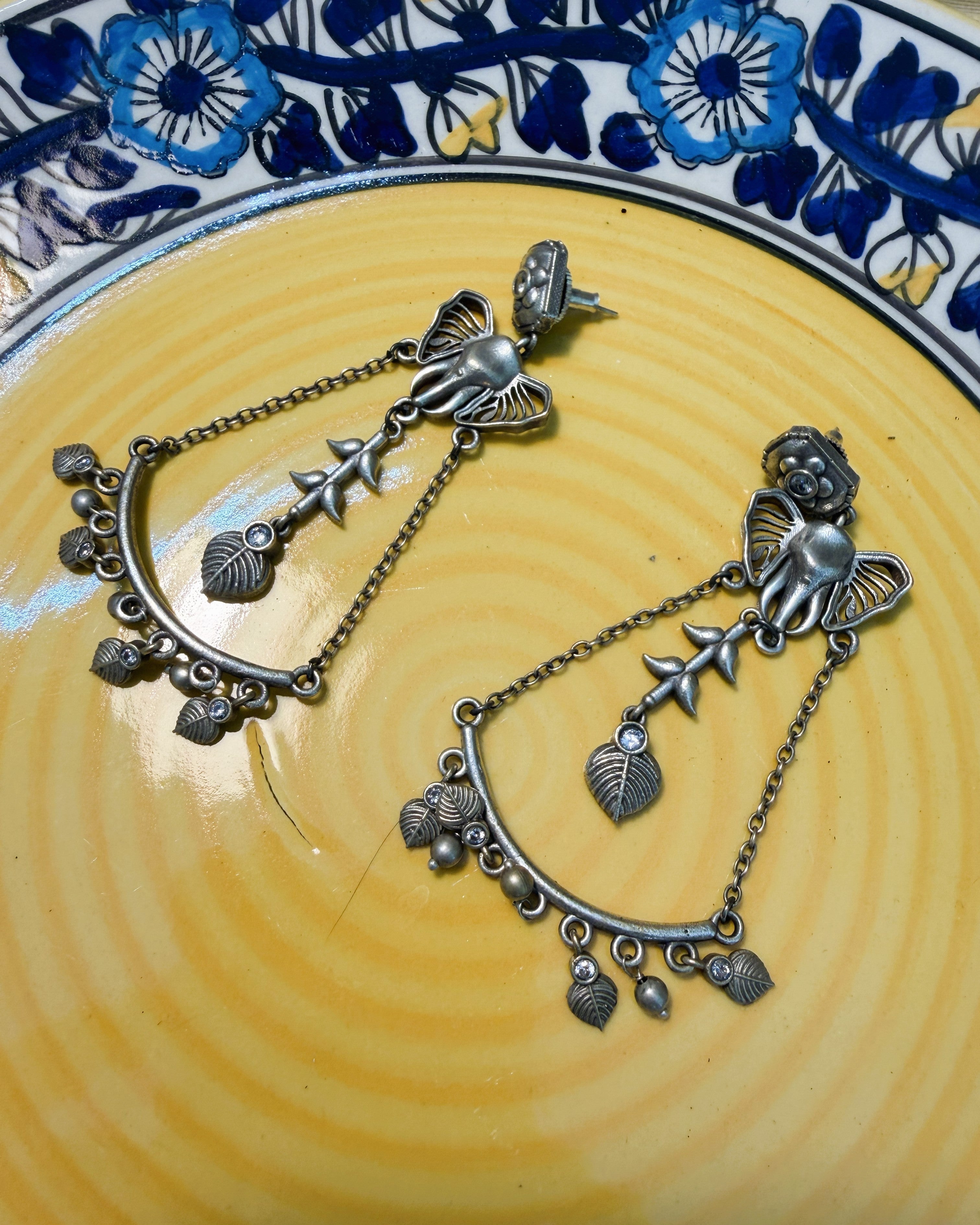 Oxidised silver Ganesha drop earrings with crescent arch, leaf charms, and crystal accent stones