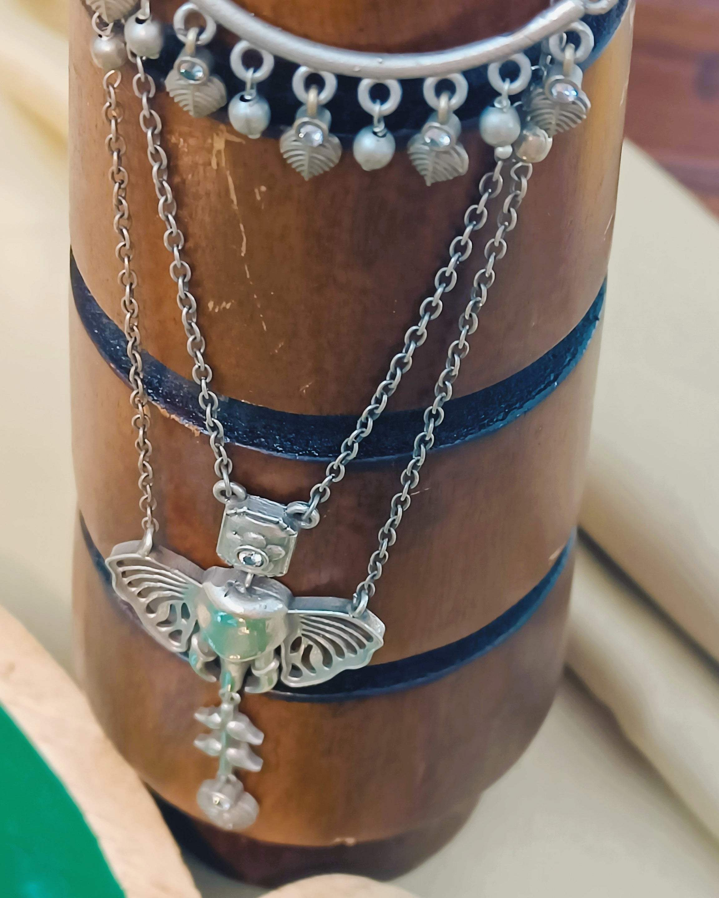 Close-up of handcrafted Ganesha pendant with butterfly-wing detailing on a multi-strand oxidised brass chain