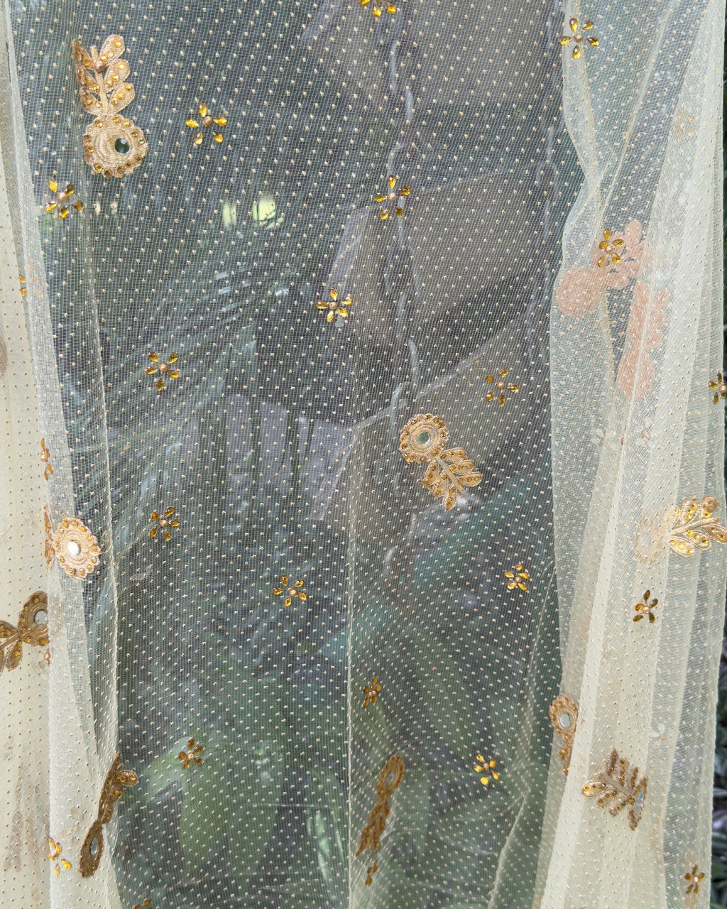 Close-up of handcrafted floral embellishments on golden net dupatta