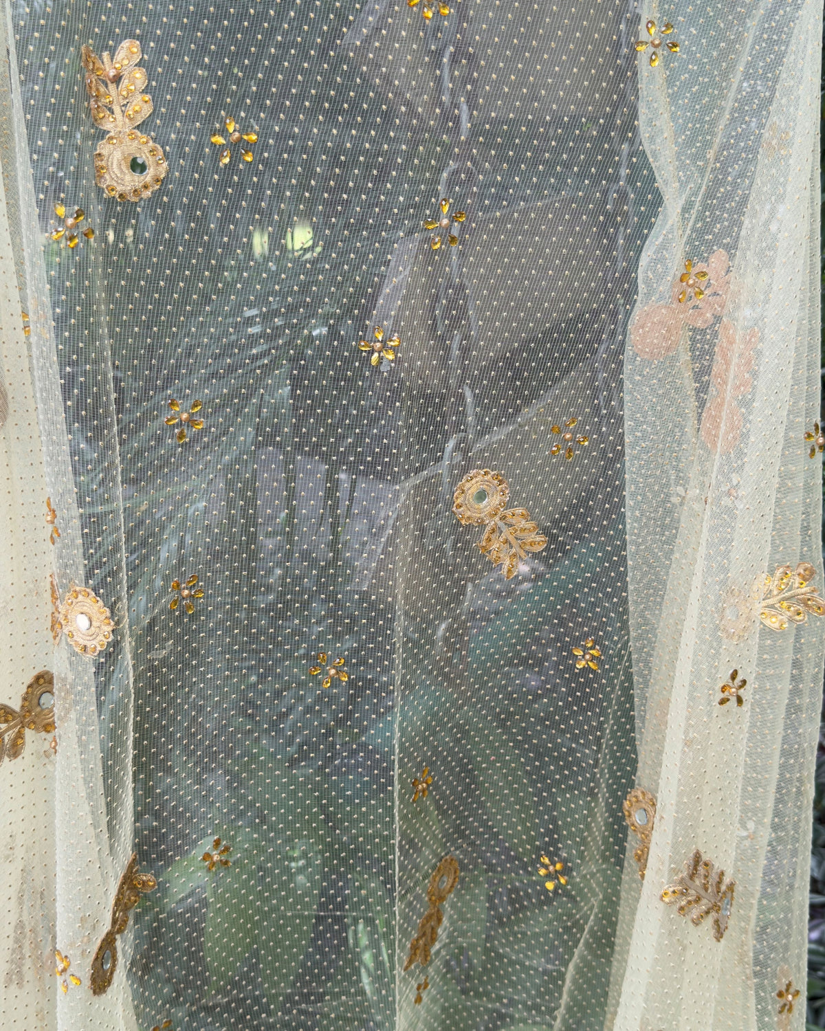 Close-up of handcrafted floral embellishments on golden net dupatta