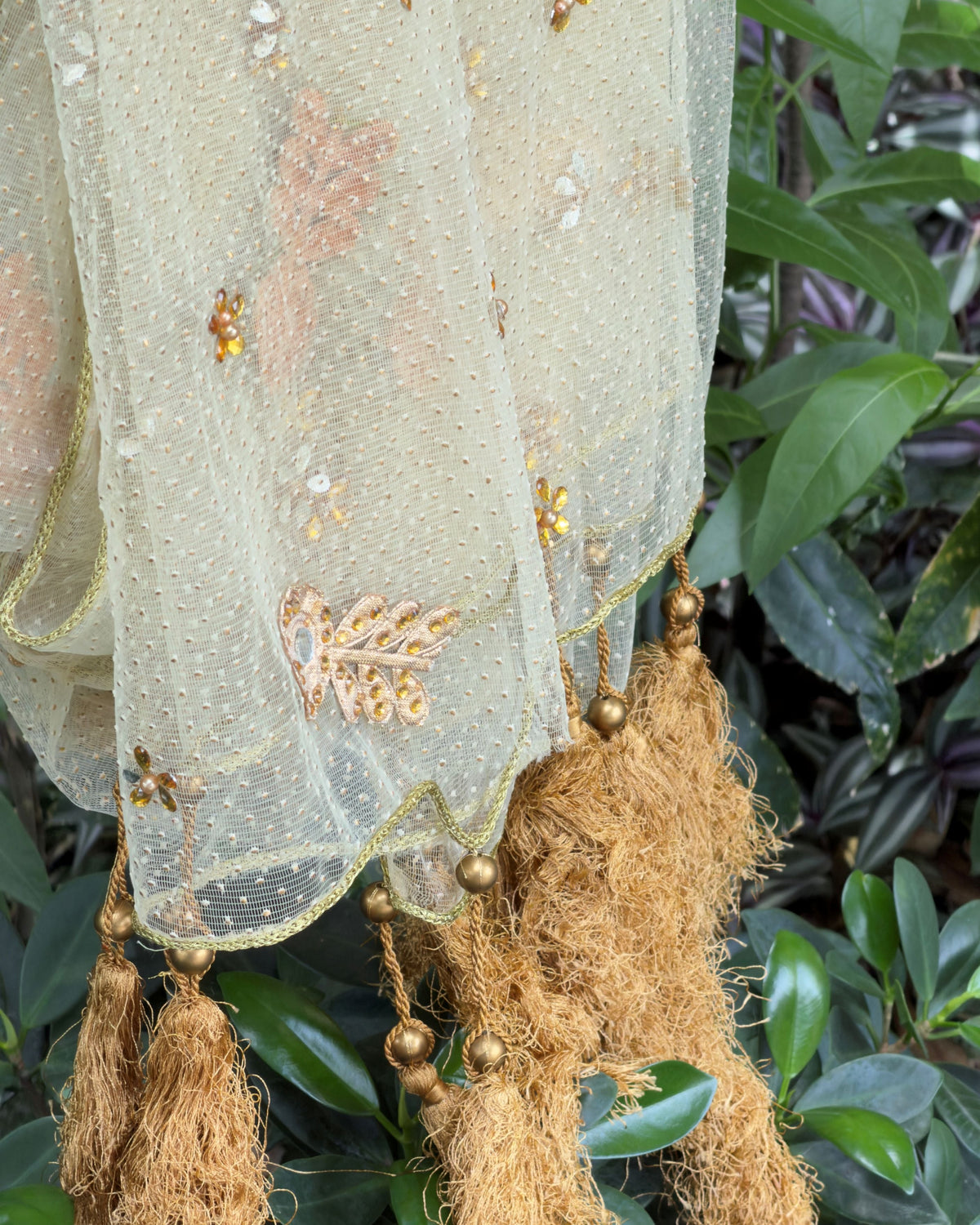 Detailed view of floral-inspired embellishments on sheer golden net fabric