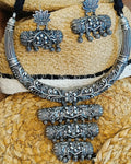 Kamal Vritti antique oxidised silver choker necklace and elephant stud earrings set displayed on a woven hat with black thread cord