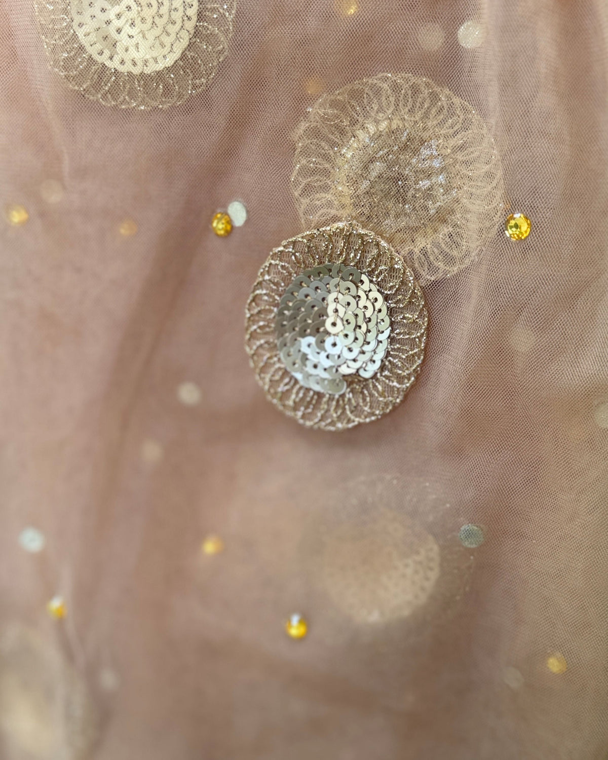 Close-up of handcrafted gold and ivory sequin motifs on light brown net dupatta