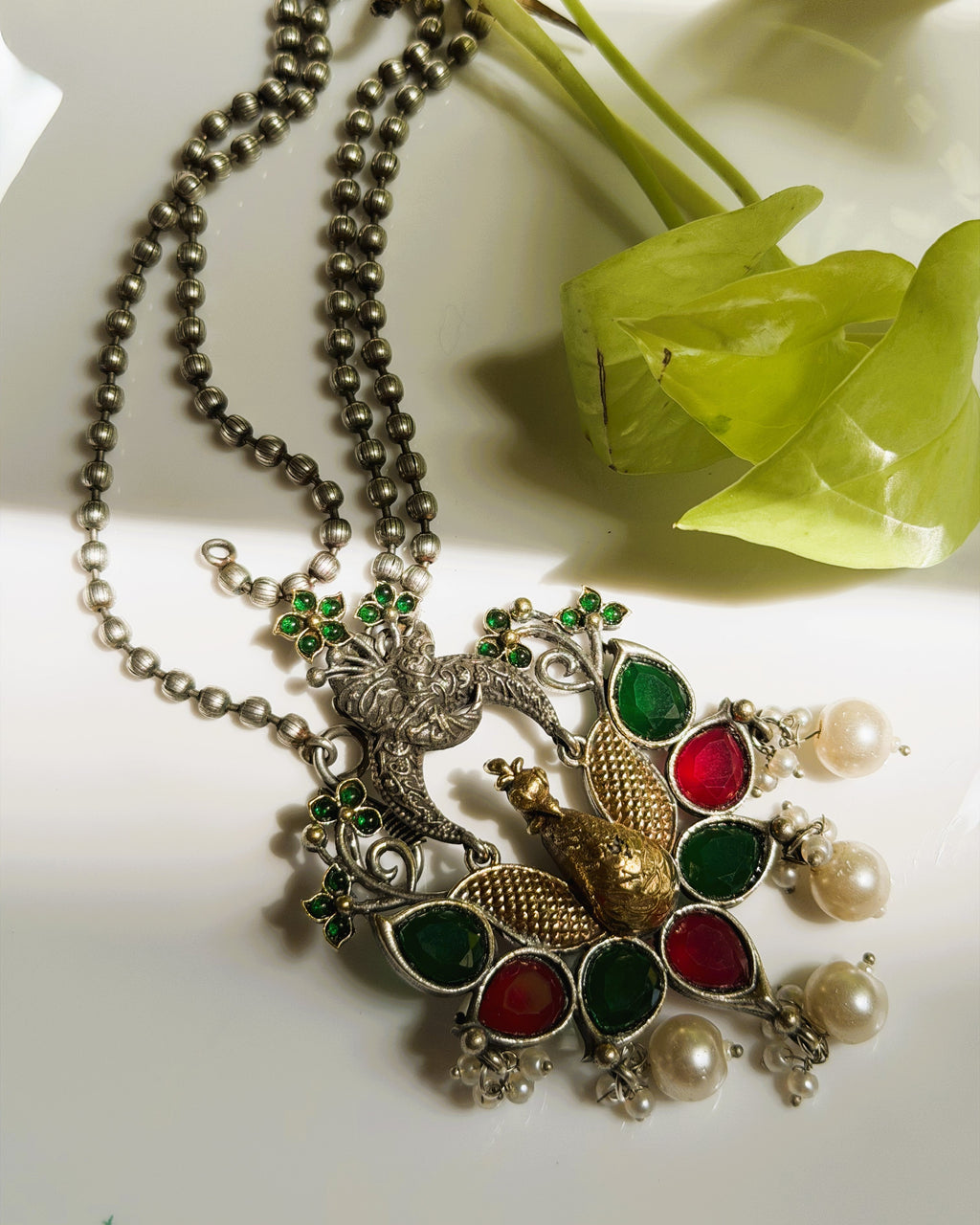 Close-up of peacock pendant with intricate carving and colorful stone detailing