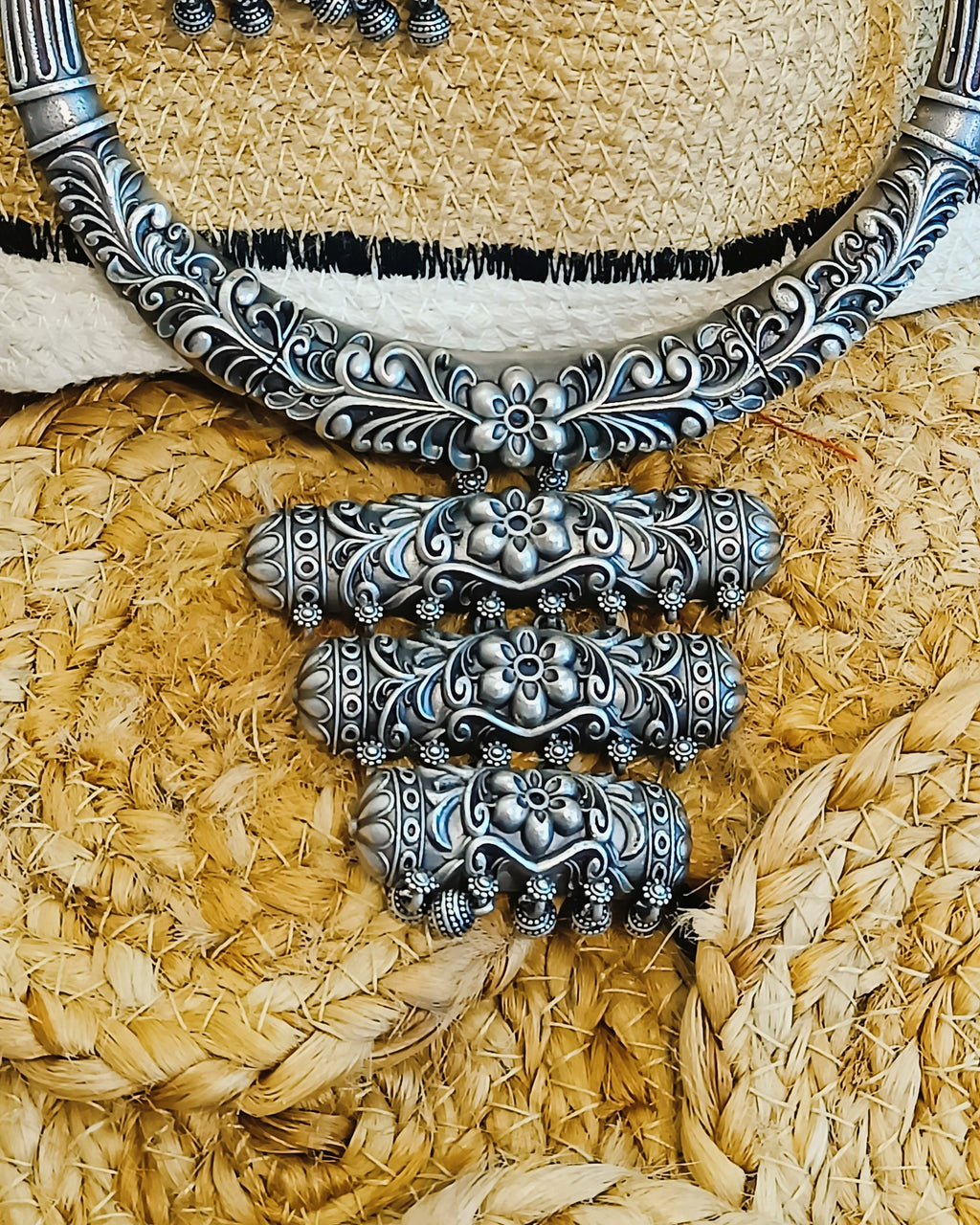 Close-up of antique oxidised silver brass choker with all-over floral scroll engraving and black braided thread cord