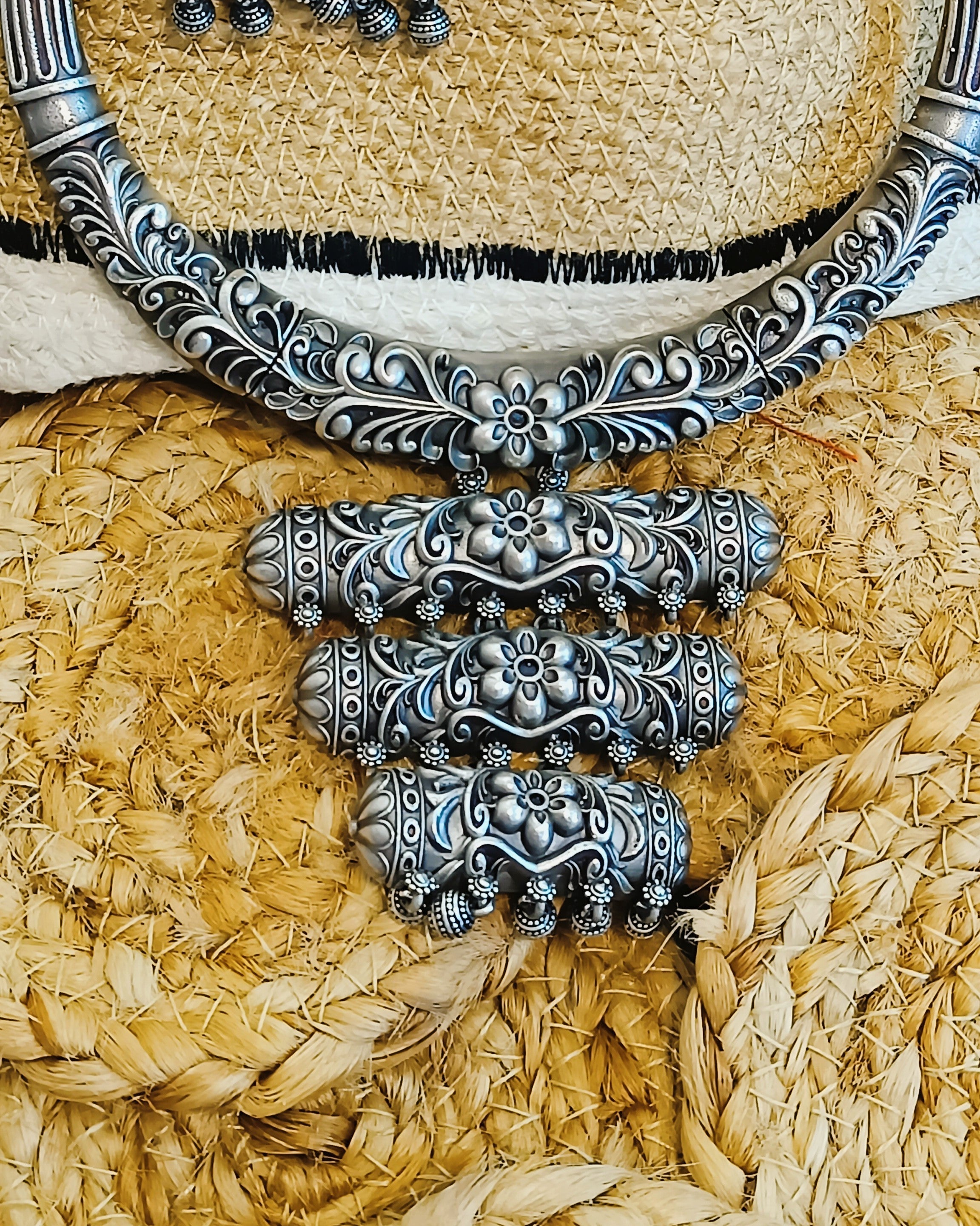 Close-up of antique oxidised silver brass choker with all-over floral scroll engraving and black braided thread cord