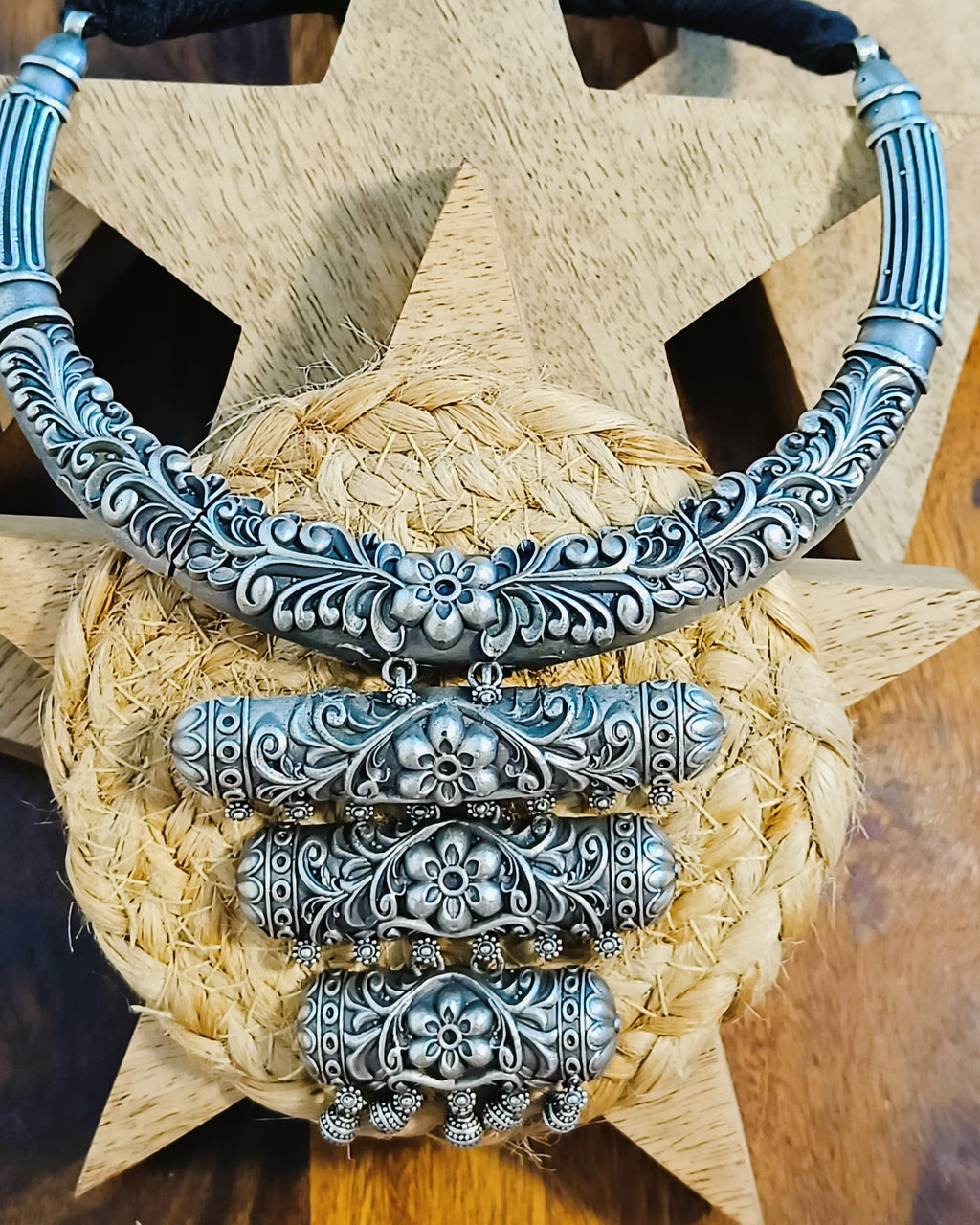 Close-up of antique oxidised silver brass choker with all-over floral scroll engraving and black braided thread cord