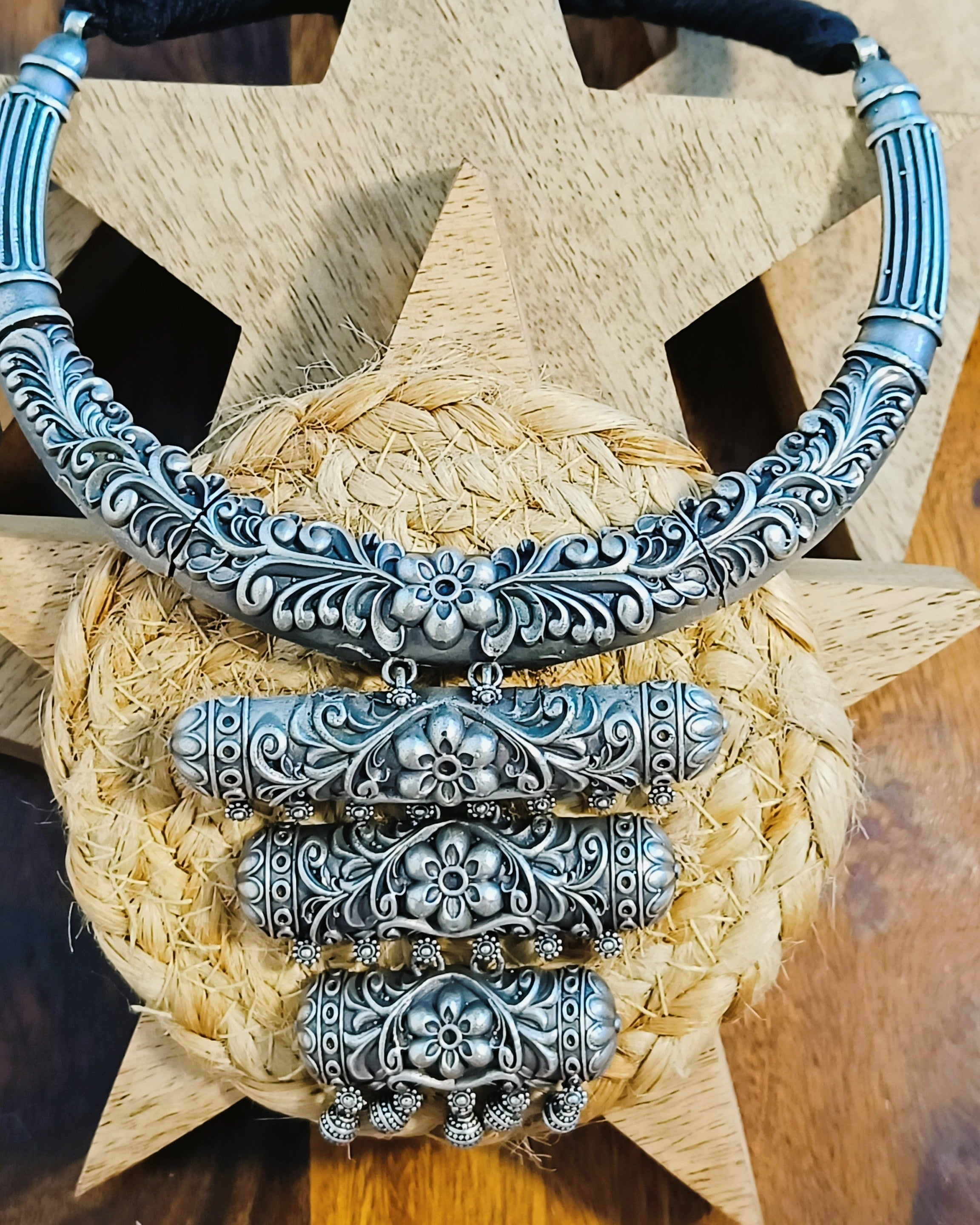 Close-up of antique oxidised silver brass choker with all-over floral scroll engraving and black braided thread cord