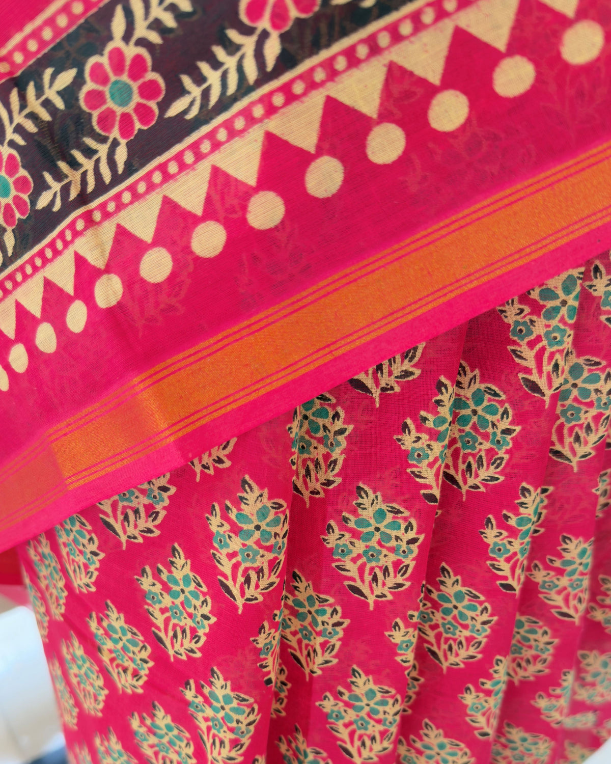 Close-up of black and teal leaf floral motifs block printed on pink cotton saree body