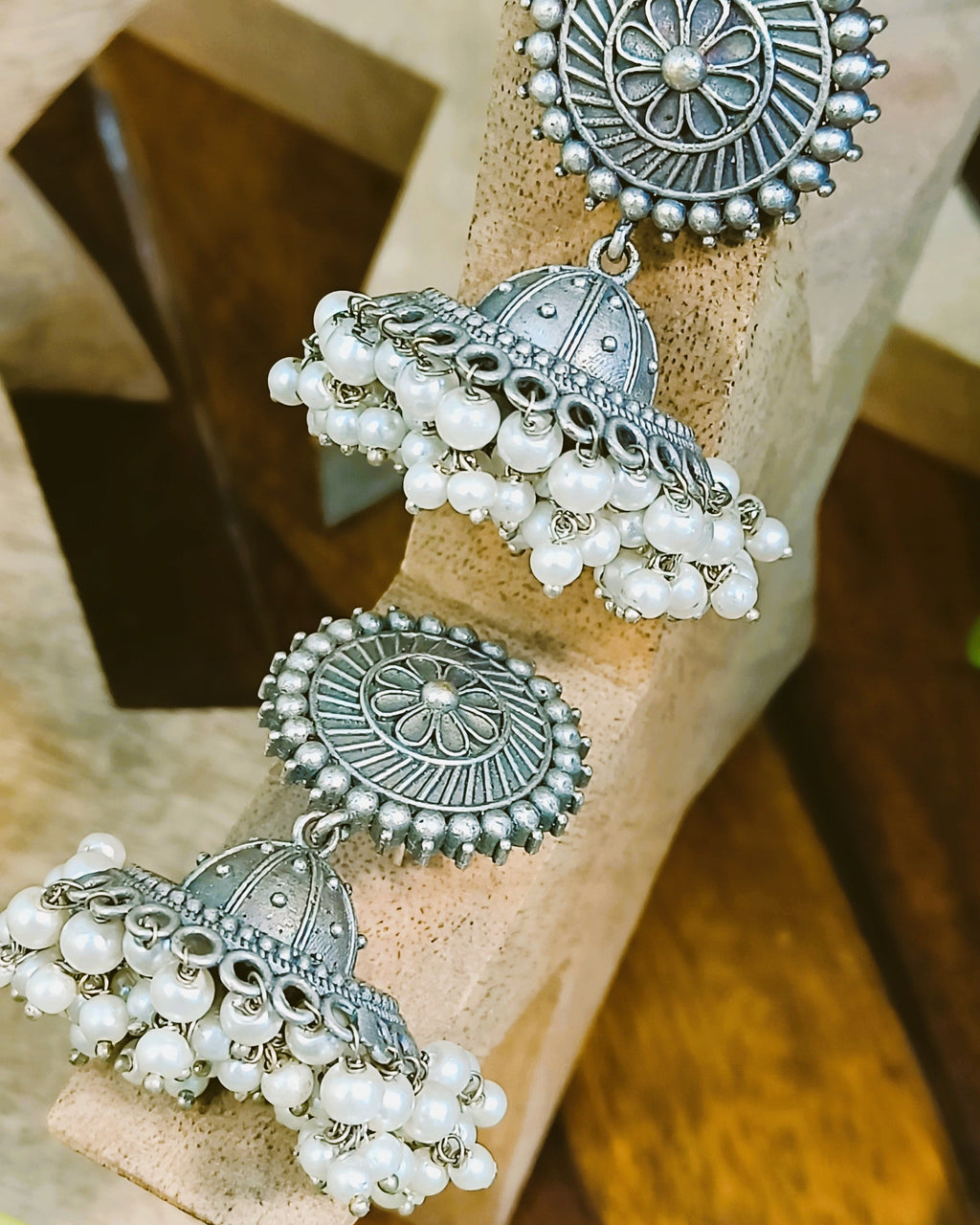 Pushpa antique oxidised silver jhumka earrings with pearl drops styled with ethnic wear showcasing the floral disc stud and domed bell design