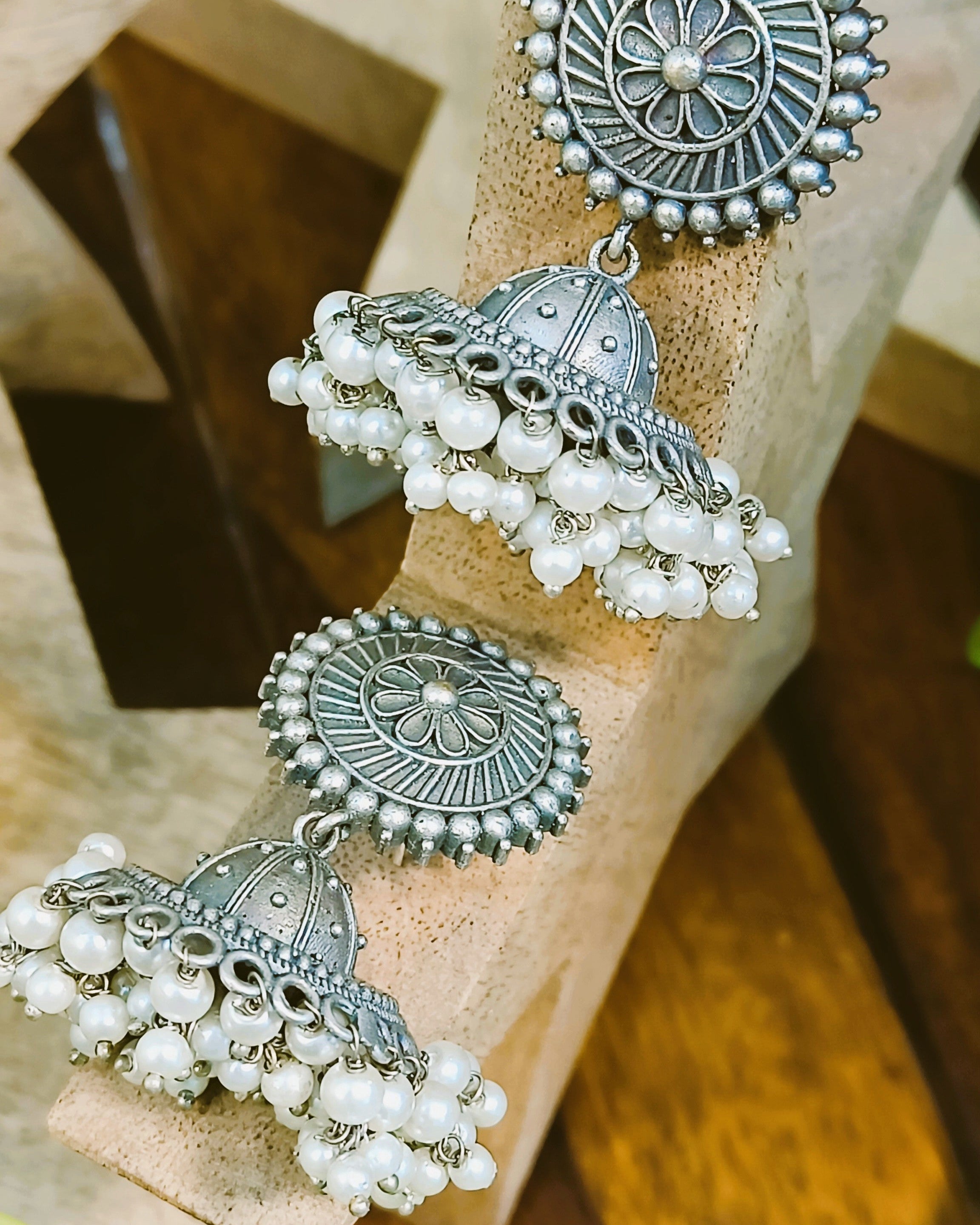 Pushpa antique oxidised silver jhumka earrings with pearl drops styled with ethnic wear showcasing the floral disc stud and domed bell design