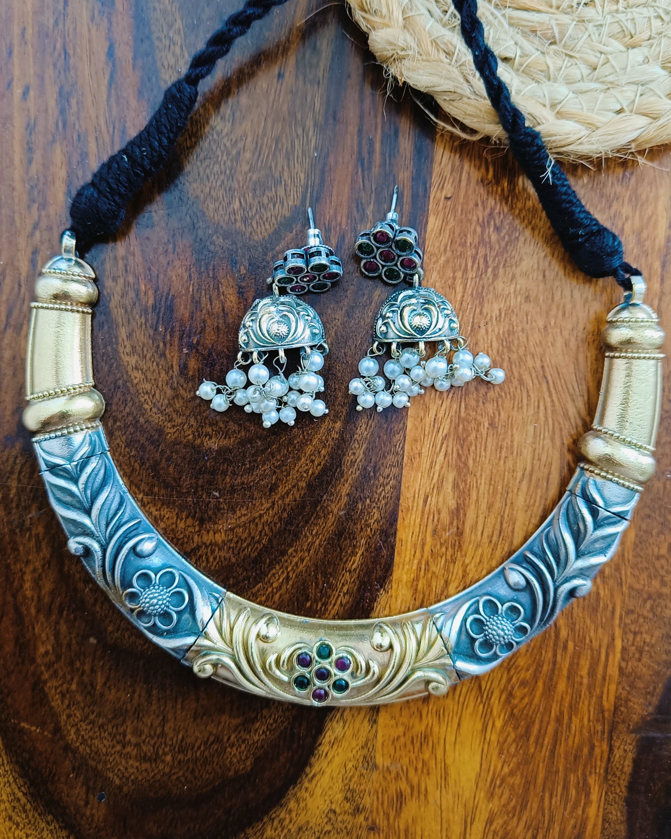 Rajwada dual tone gold and oxidised silver choker necklace set with jhumka earrings displayed on a wooden jewellery stand