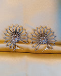 Surya Chakra antique oxidised silver sunburst stud earrings with open-work geometric rays displayed on a green wooden tray