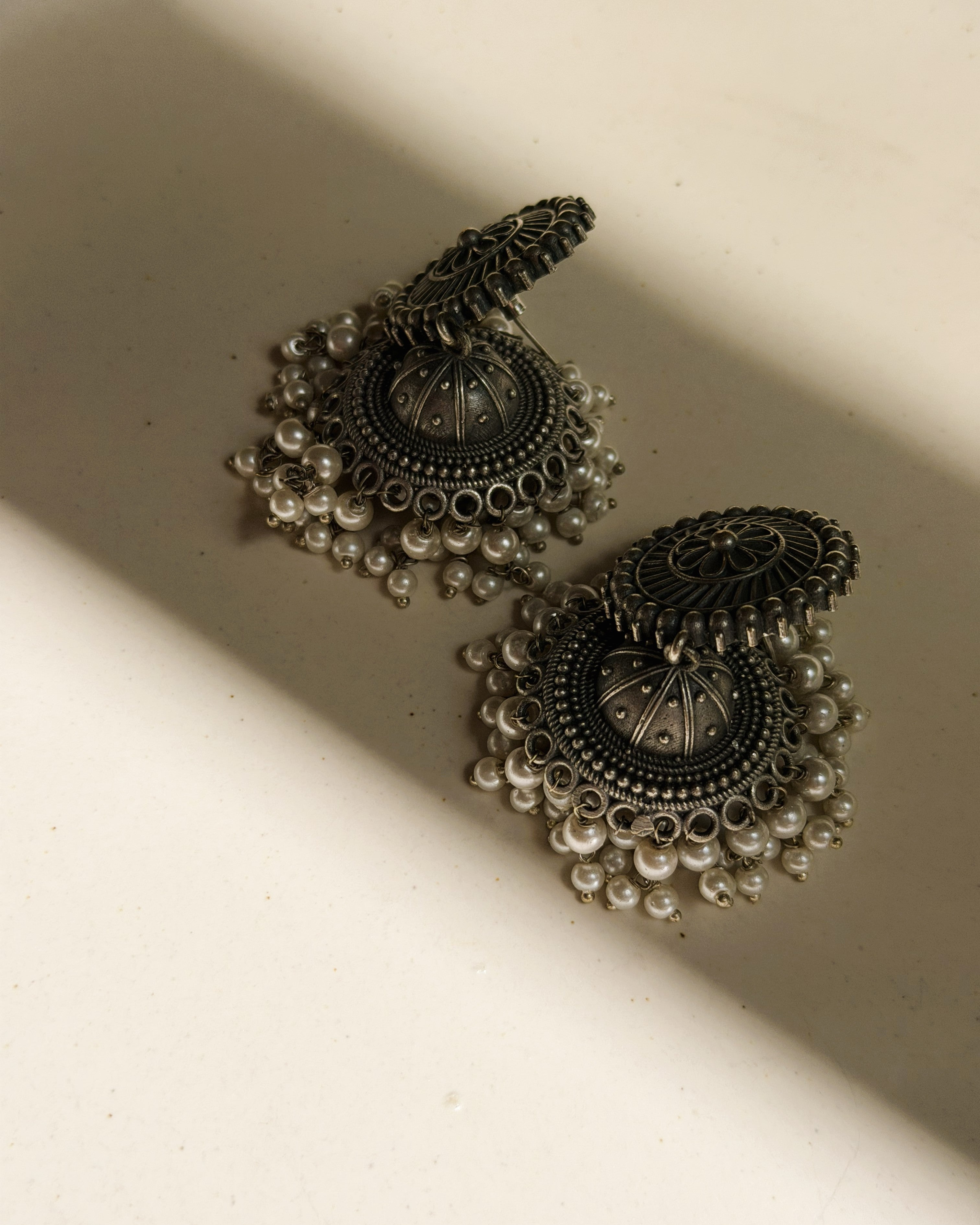 Close-up of the cascading white seed pearl drop fringe along the base of the Pushpa antique oxidised silver jhumka earring