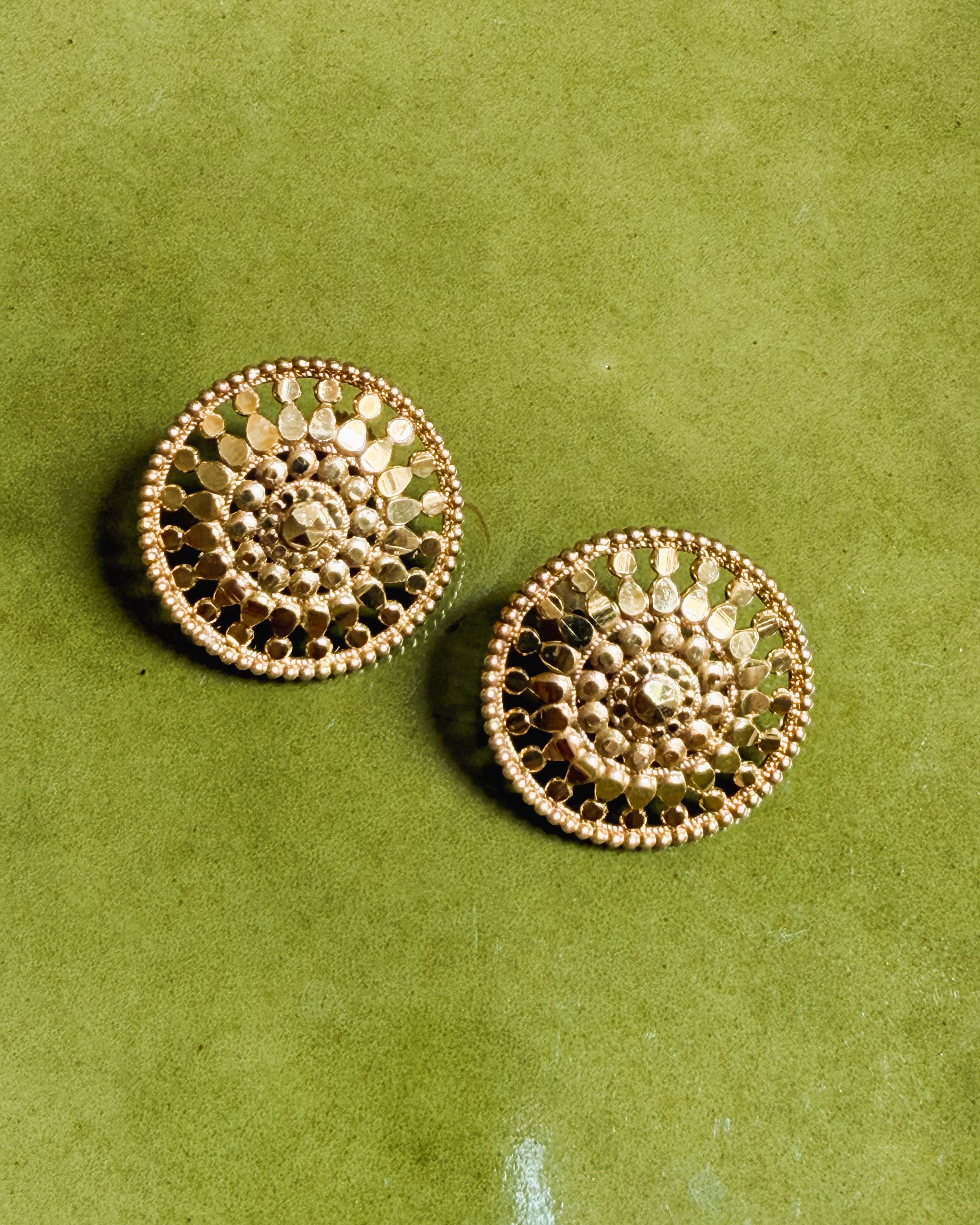 Flatlay of gold floral earrings on soft neutral background