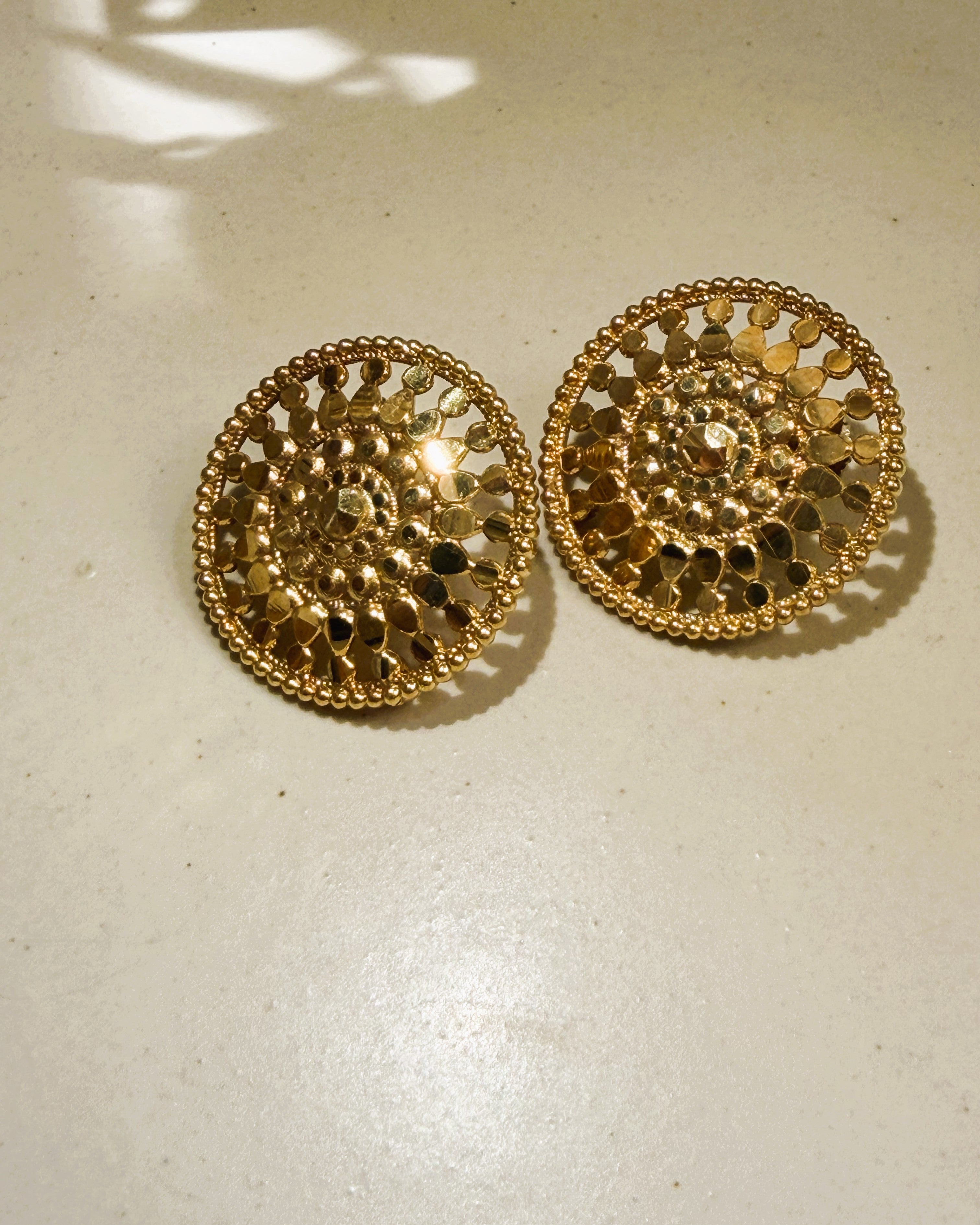 Circular gold earrings featuring floral inspired openwork design